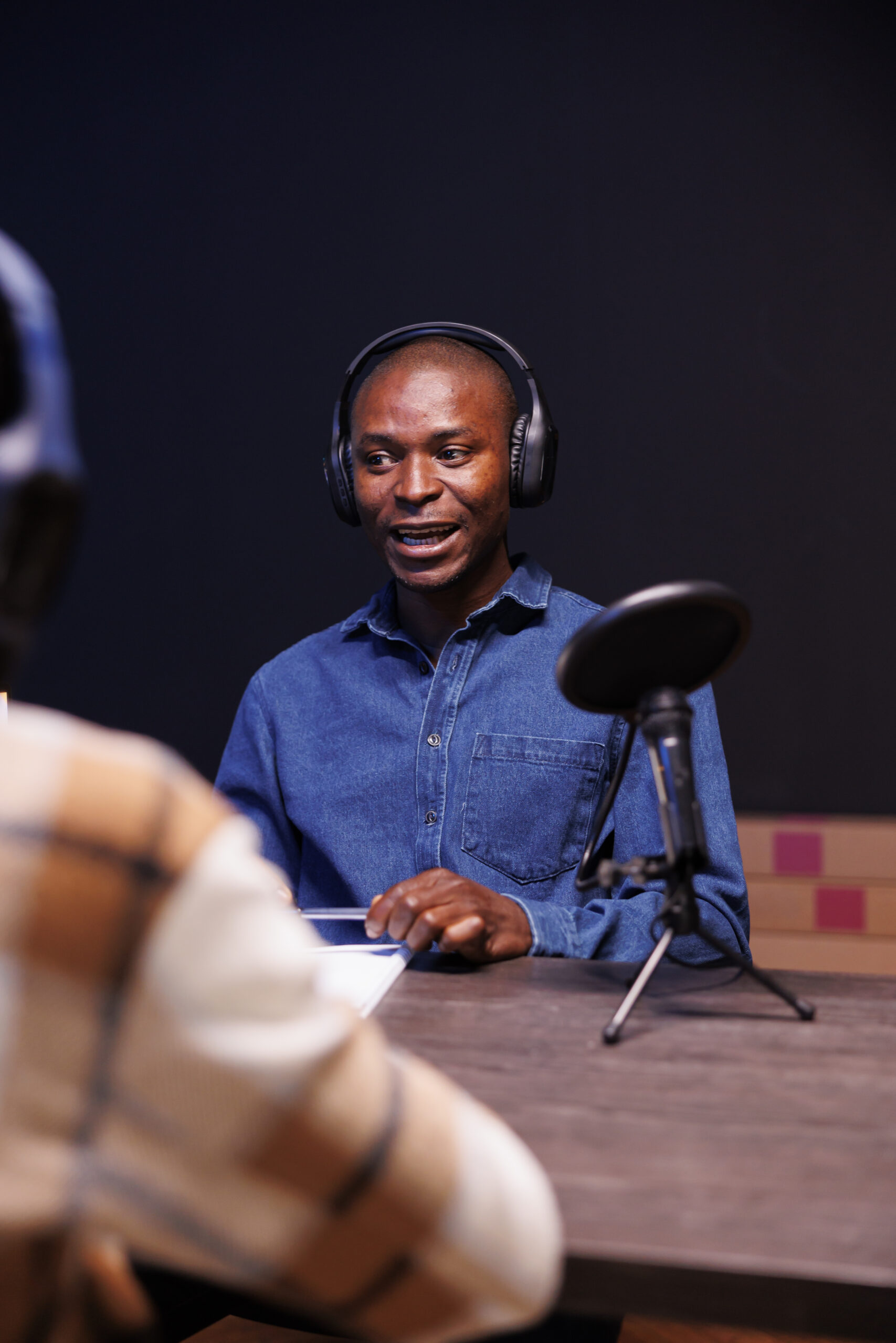 Black male guest speaking into microphone, answering questions from radio program host. African american man being interviewed using audio equipment to record an online talk show at home.